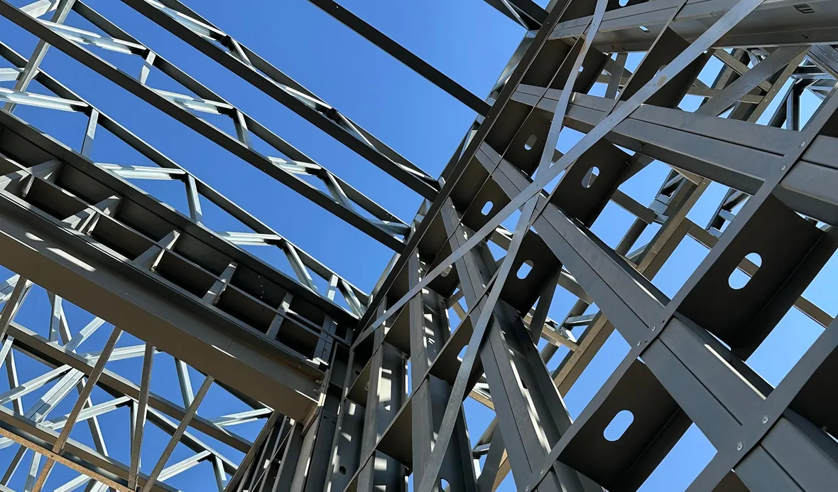 Looking up through a light gauge steel wall and roof frame against a blue sky