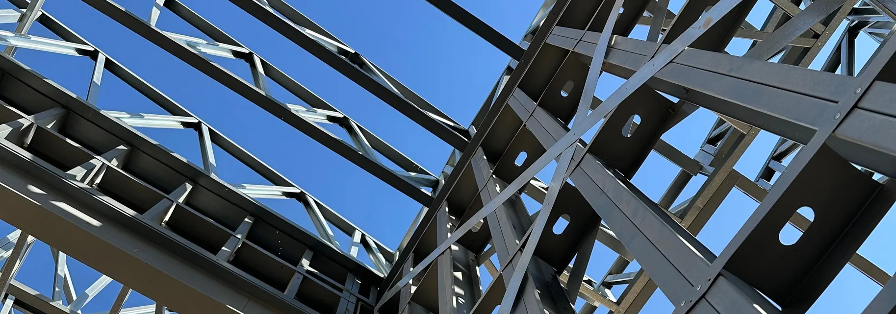 Looking up through a light gauge steel wall and roof frame against a blue sky