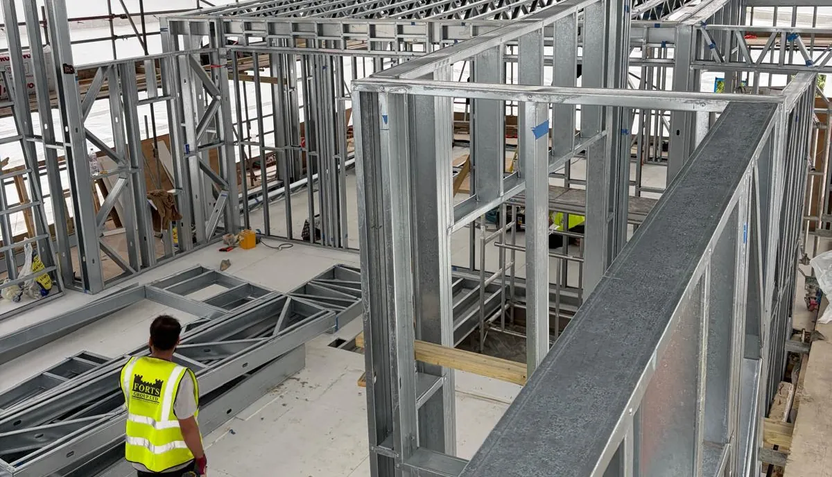 Forts Group operative walking through a light gauge steel frame under a temporary roof on a constrained site